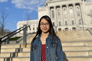 Undergraduate student, Bianca Yue, standing in front if the state Capitol building with blue sky in the background.