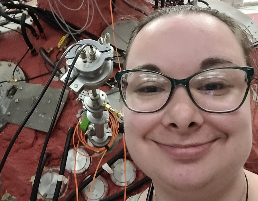 Amanda Ready is posed, smiling in this selfie taken in front of the probe that she designed for her senior thesis research in the Physics department.
