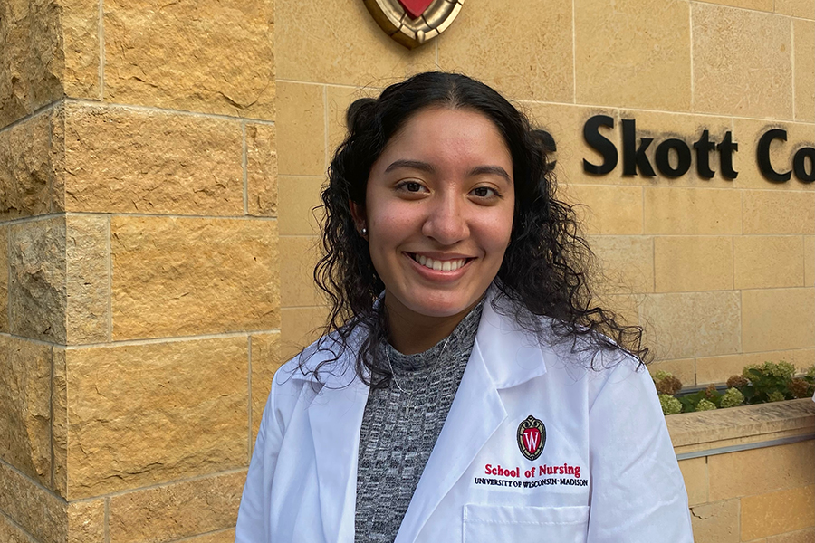 Annaly Garcia smiles wearing her BS white coat in front of Signe Skott Cooper Hall.