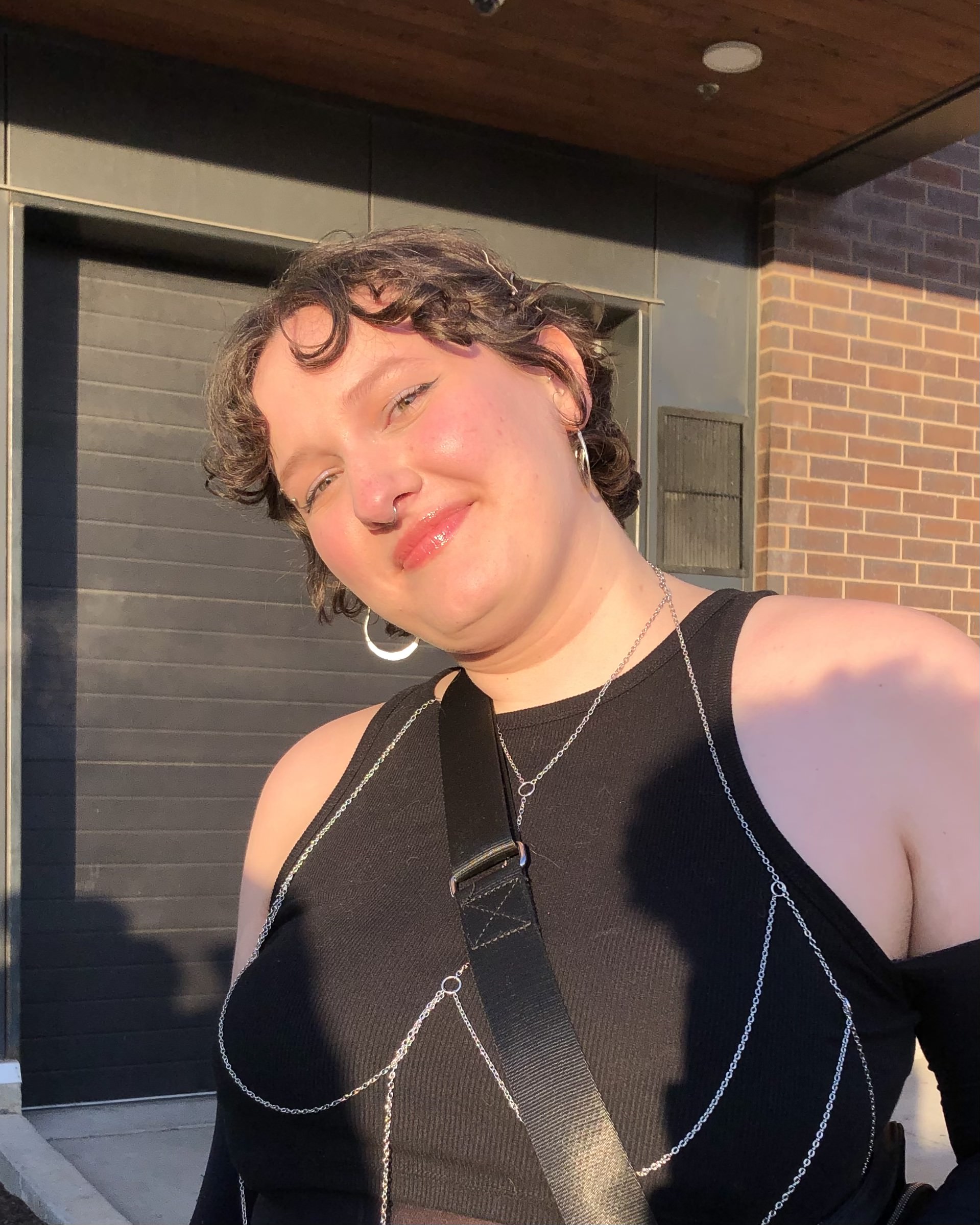 Ella Deitz smiling at the camera with short brown hair wearing a black sleeveless outfit.