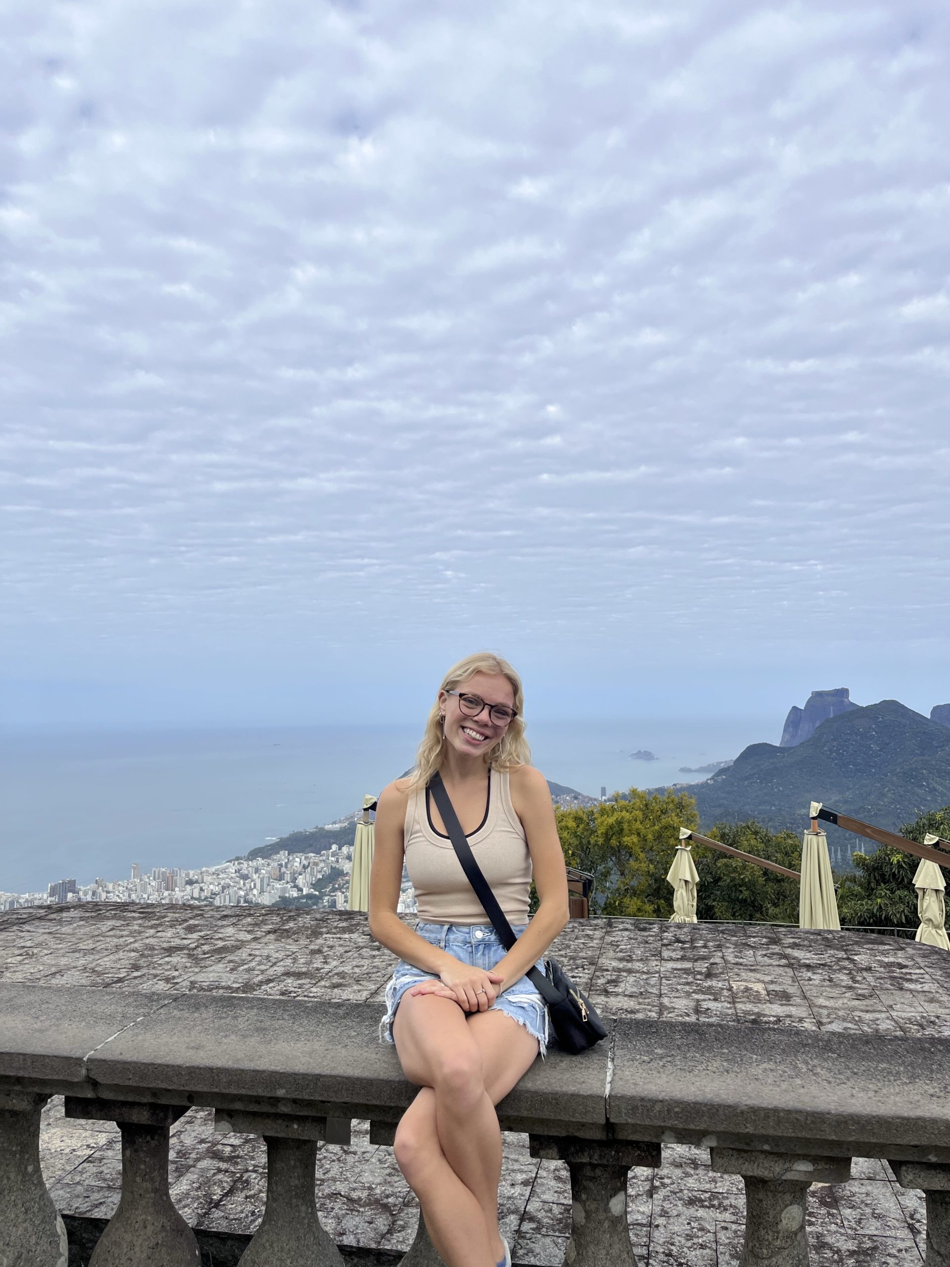 image of Stephanie Kressin with blonde hair and glasses sitting outside smiling at the camera